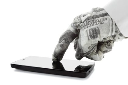 A hand wrapped in $100 bills touches a smartphone.