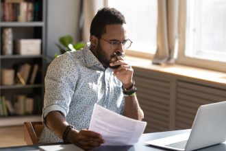An investor looks pensively at something on a laptop.