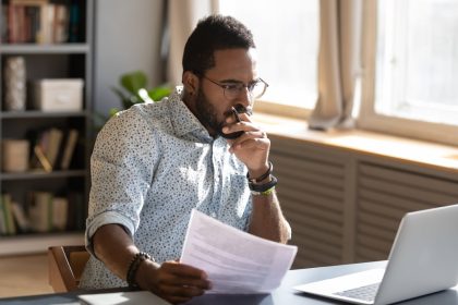 An investor looks pensively at something on a laptop.