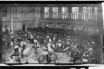 A 1907 documentary photograph shows brokers working across the crowded New York Stock Exchange trading floor in New York.